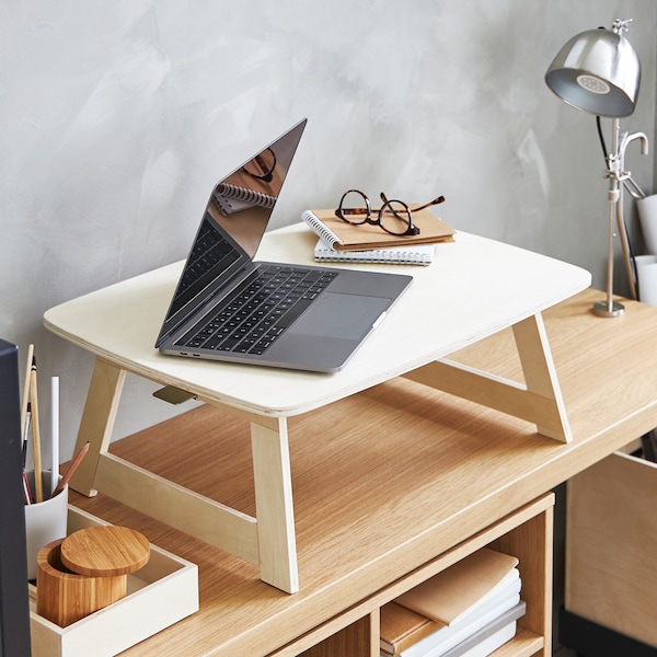 A foldable birch plywood tray and spectacles on top of an oak veneer console table with a clamp table lamp at one side.