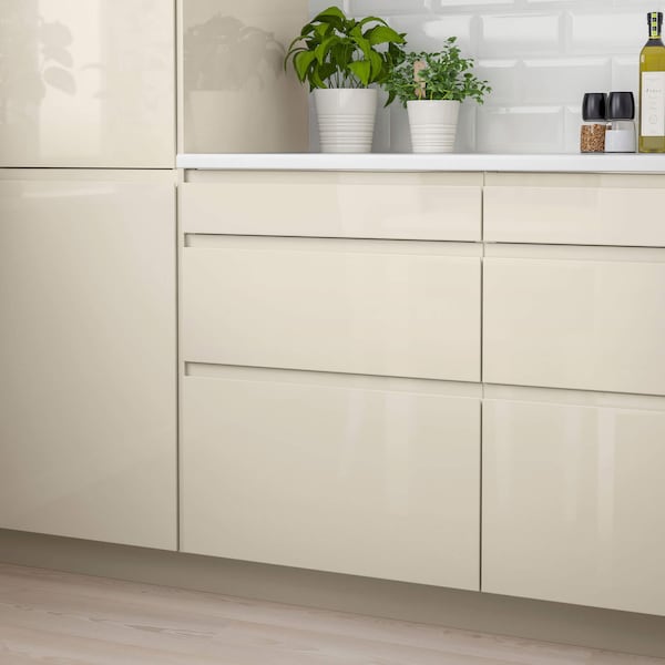 A high-gloss beige set of cabinets with a white countertop.