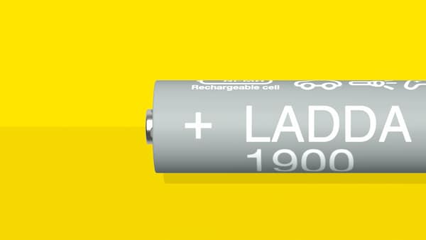 A LADDA rechargeable battery, HR06 AA, with a battery capacity of 1900mAh, is lying on a yellow surface.