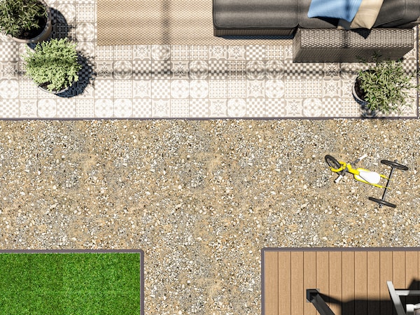 A large outdoor space with three different types of floor decking, outdoor furniture, a child’s tricycle and potted plants.