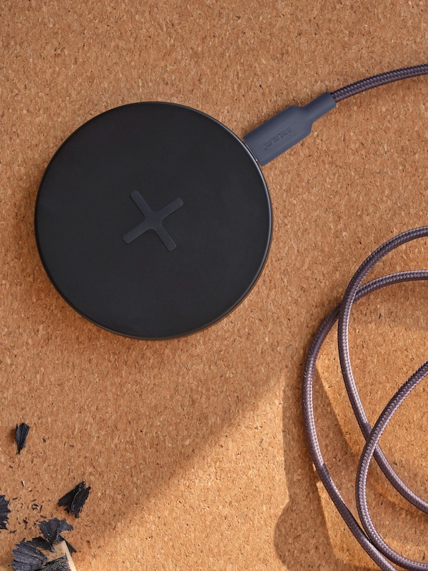 A LIVBOJ wireless charger with a LILLHULT USB-A to USB-C cable connected to it sits on a cork desk pad.