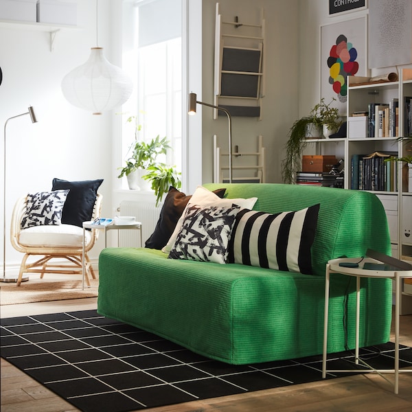 A small studio with a LYCKSELE LÖVÅS sofa-bed in Vansbro bright green cover, black and white textiles and an armchair.