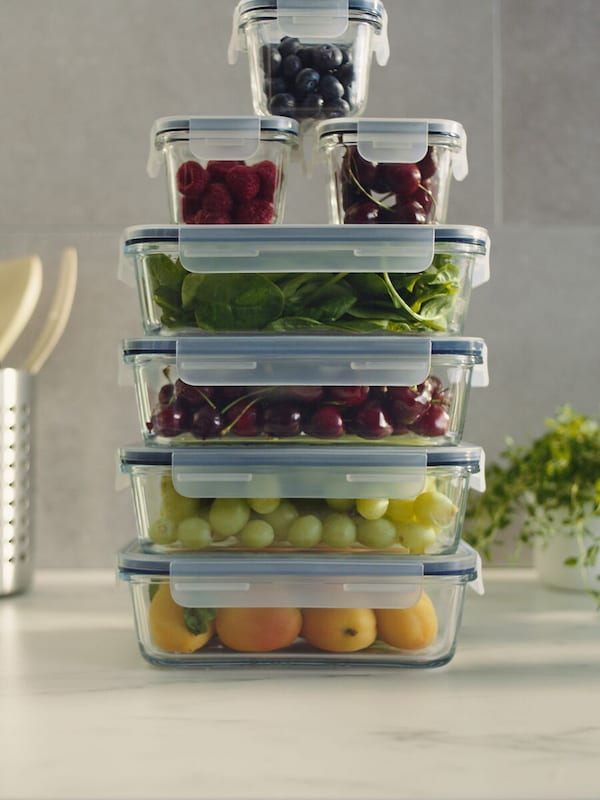 A stack of several food containers of different-sizes, with fruits and vegetables inside.