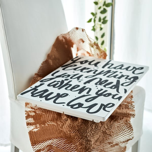 A SYMFONISK picture frame with WiFi speaker with a panel with a message about love lying on some netting on a chair.