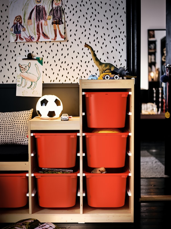 A toy-filled TROFAST unit with orange storage boxes in a kids’ room set in an otherwise black-and-white color scheme.