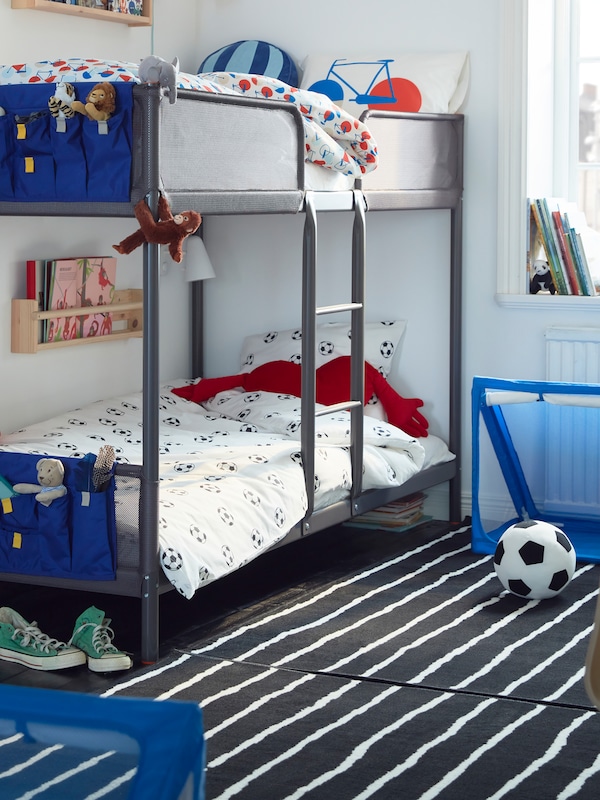 A TUFFING bunk bed in a children’s room, with a football and a goal on the floor. Blue pockets are at the end of each bed.