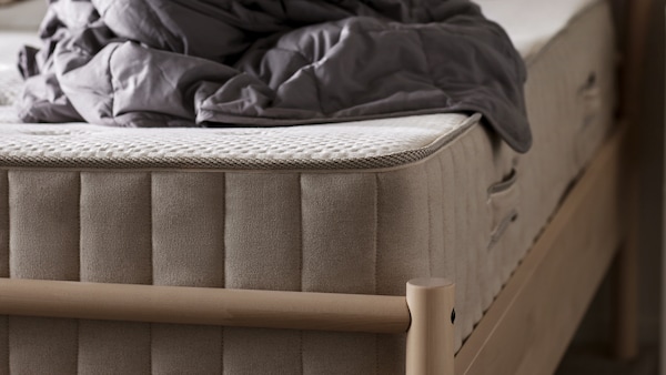 A VATNESTRÖM pocket spring mattress with a crumpled up ODONVIDE weighted blanket on top of it lies on a BJÖRKSNÄS bed frame.