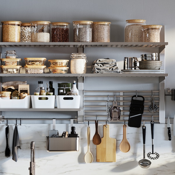 A wall-mounted KUNGSFORS kitchen storage series with glass jars with lids, white VARIERA storage boxes and hanging utensils.