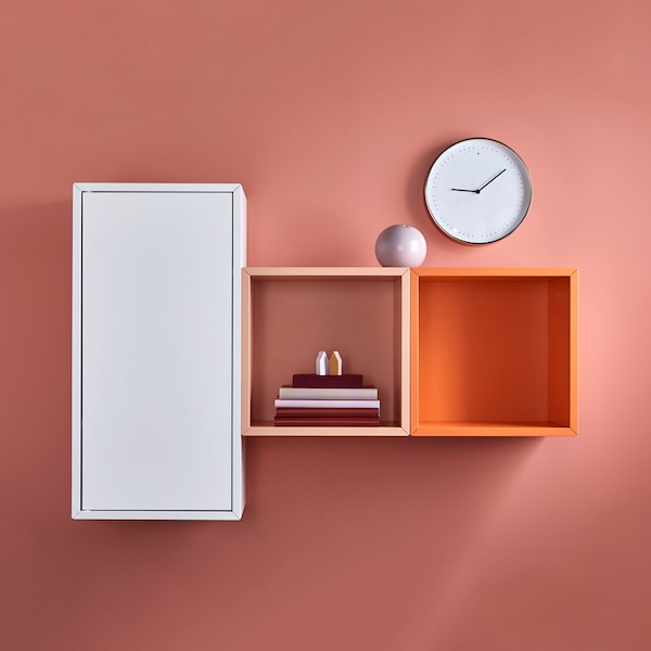 A white EKET cabinet with door hangs beside two EKET cabinets against a peach wall.