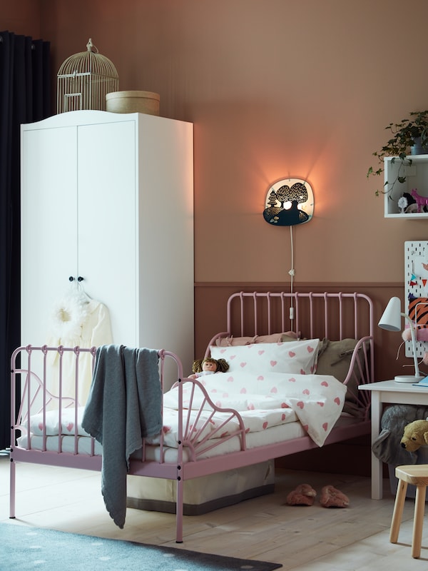 A white SMÅGÖRA wardrobe stands in a kid’s room near a MINNEN extendable bed with BARNDRÖM bed linen.