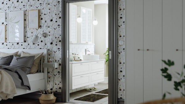 An open door leading to a bathroom with GODMORGON mirror cabinets with two doors and a TOLKEN marble effect countertop.