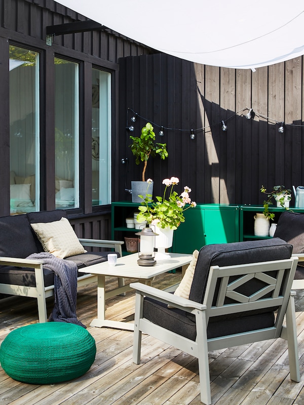 An outdoor space with BONDHOLMEN sofa, armchairs and a coffee table in grey.