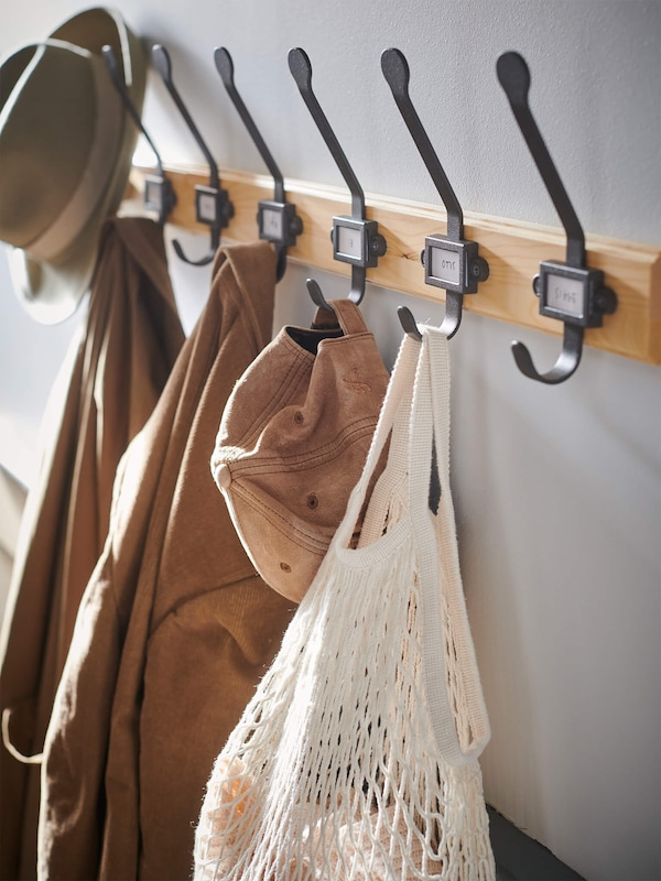 Coat rack with wrought metal and treated wood holding garments in Scandi modern style home. 