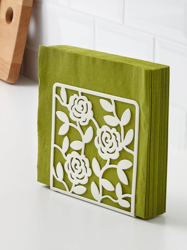 Decorative napkin holder with a design featuring roses holding green napkins on the kitchen counter. 