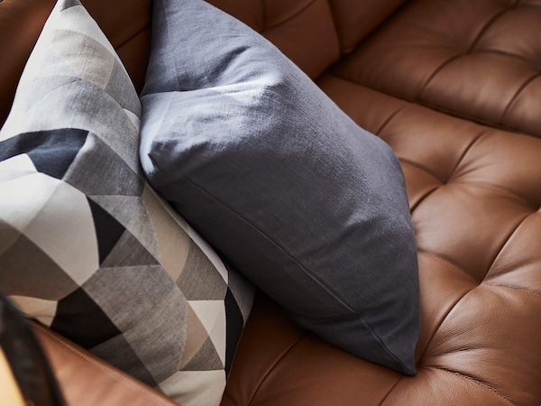 Decorative pillows on tan leather couch. 