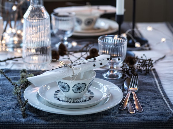 Decorative stoneware, utensils & glassware on dining room table.