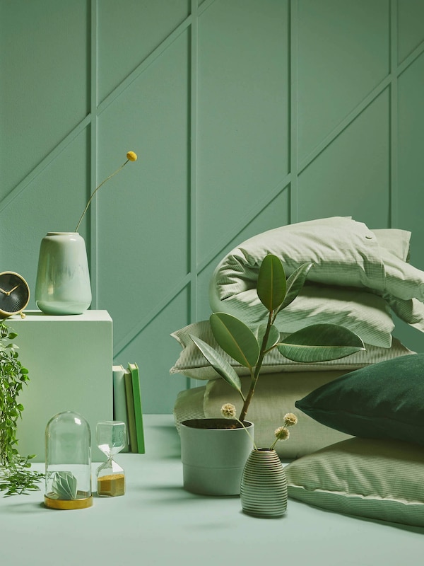 Green bedroom with green plants, pillows and blankets. 
