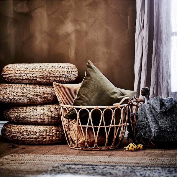 Handwoven rattan basket holding pillows by a stack of woven seat