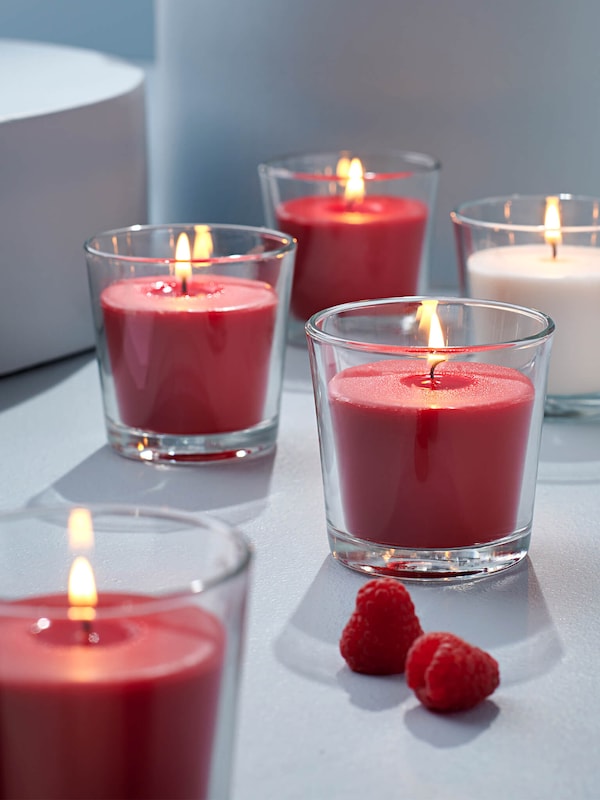 Lit red candles in glass vases in a minimalist, modern decor setting. 