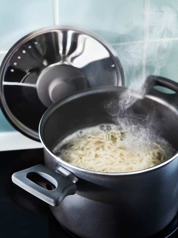 Noodles cooking in a pot on an electric stove. 