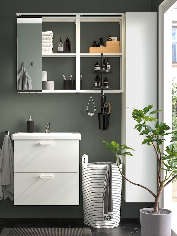 A bathroom with an ENHET sink with two drawers in white, a mirror cabinet, hanging towels and a plant by a window.
