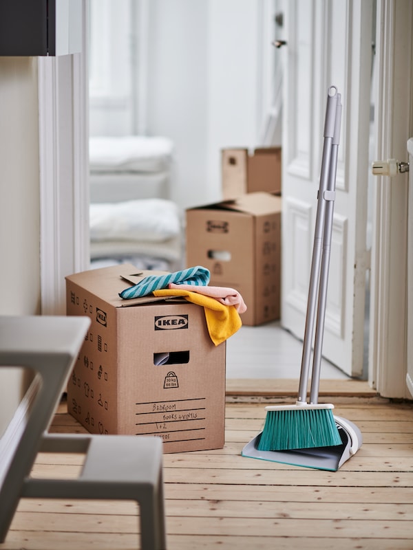 A PEPPRIG dustpan and broom and PEPPRIG microfiber cloths occupy a doorway together with several DUNDERGUBBE moving boxes.