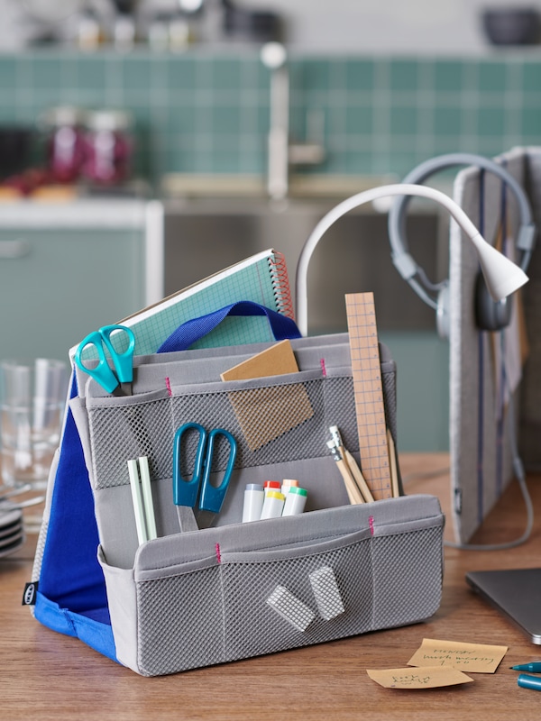 A desktop with an ÖVNING organizer filled with office accessories, standing next to an ÖVNING desk divider.