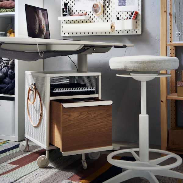 A white BEKANT desk and drawer unit, a beige LIDKULLEN sit/stand support, a white SKÅDIS pegboard and two shelving units.