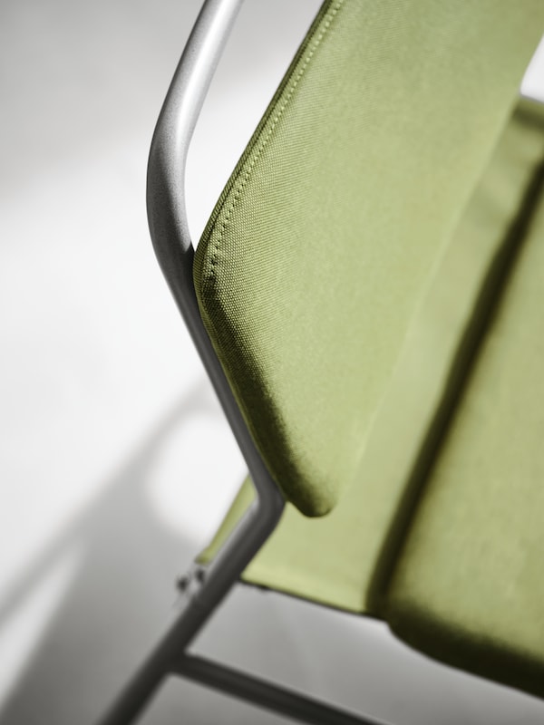 The top of the frame and the backrest and seat of a LINNEBÄCK easy chair with a black metal frame and an olive green cover.