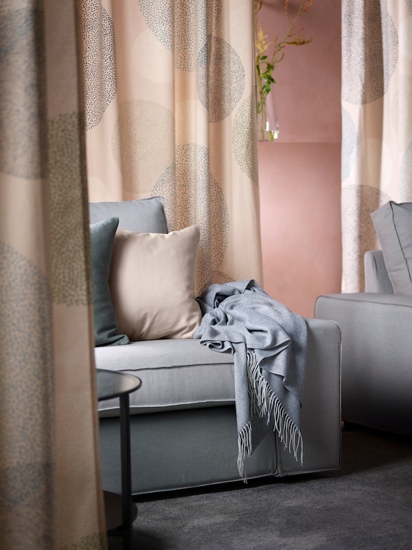 An area in a room with two light grey KIVIK three-seat sofas is divided off by hanging SANDÄNGSFLY curtains.