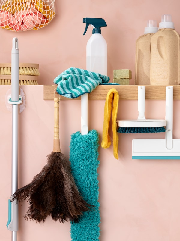 PEPPRIG microfiber cloths, a PEPPRIG spray bottle and other cleaning items neatly arranged on a pink wall.
