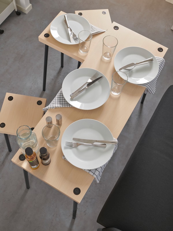 FRIDNÄS nesting tables with two stools set up for a simple dinner party using the stools and sofa as seats for four people.