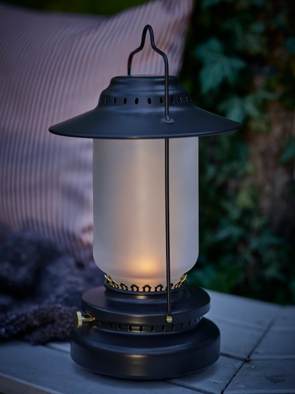 A lit STORHAGA dimmable LED table lamp placed on a bench in dim light.