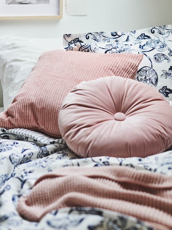 Pink pillow on top of blue and white bed spread