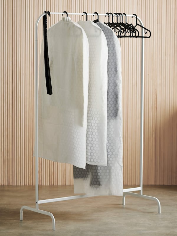 Portable clothes rack with clothes in bags. 