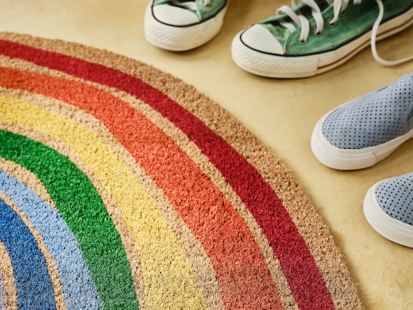 Rainbow color low pile fabric rug next to sneakers. 