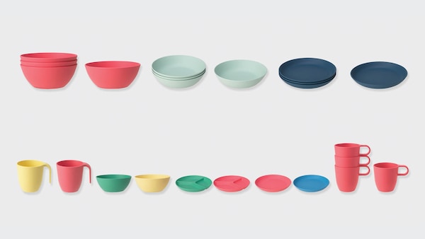 Several colorful bowls, plates, and cups lined up in a row against a gray background.