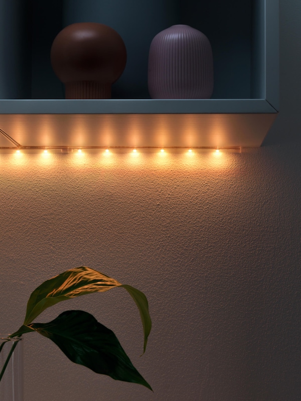 Soft amber glow of LED strip lighting underneath shelving.