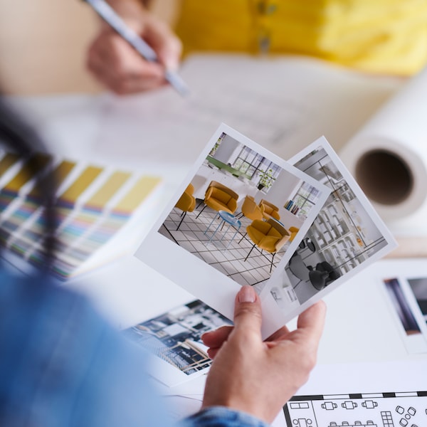 Two people by a desk with colour swatches, room sketches and a floor plan between them.