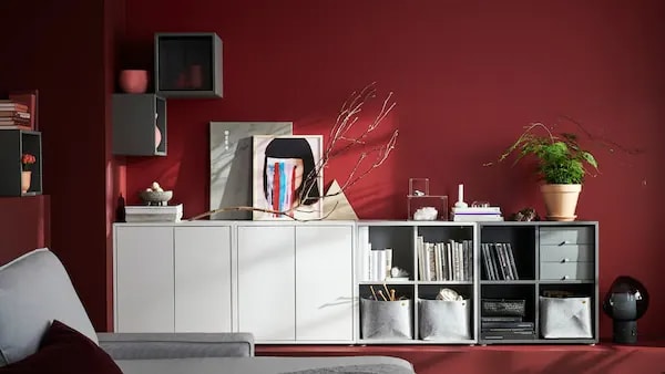 White storage cubes combined to create a storage cabinet against a red wall.