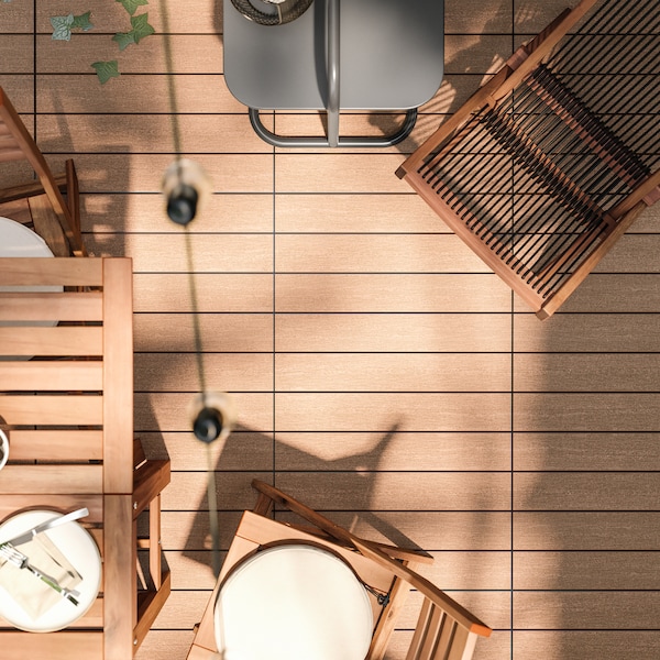 Wood-like floor decking with a wooden outdoor dining set, wooden lounger and a side table surrounding it.